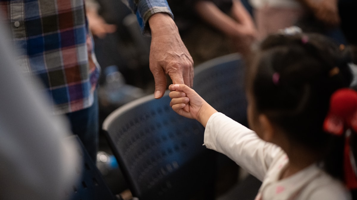 Adult hand holding a child's hand in a moment of support